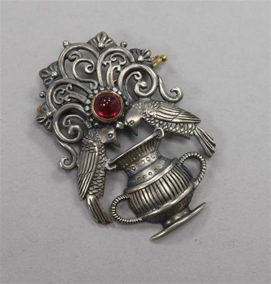 A silver and cabochon ruby set brooch, modelled as two birds on an urn with scrolling finial, 40mm.